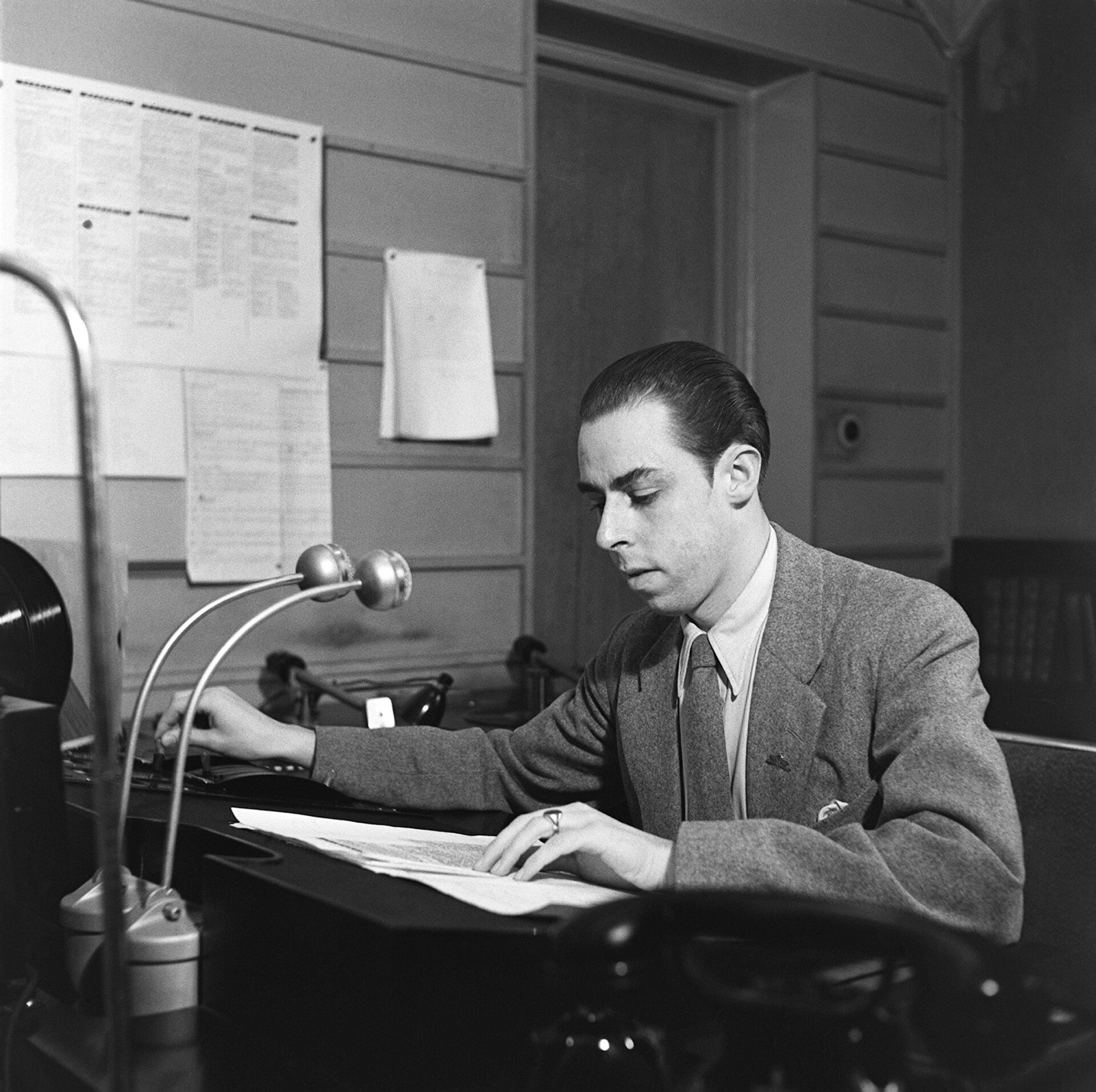 A radio announcer reading the news at two microphones in the 1930s.